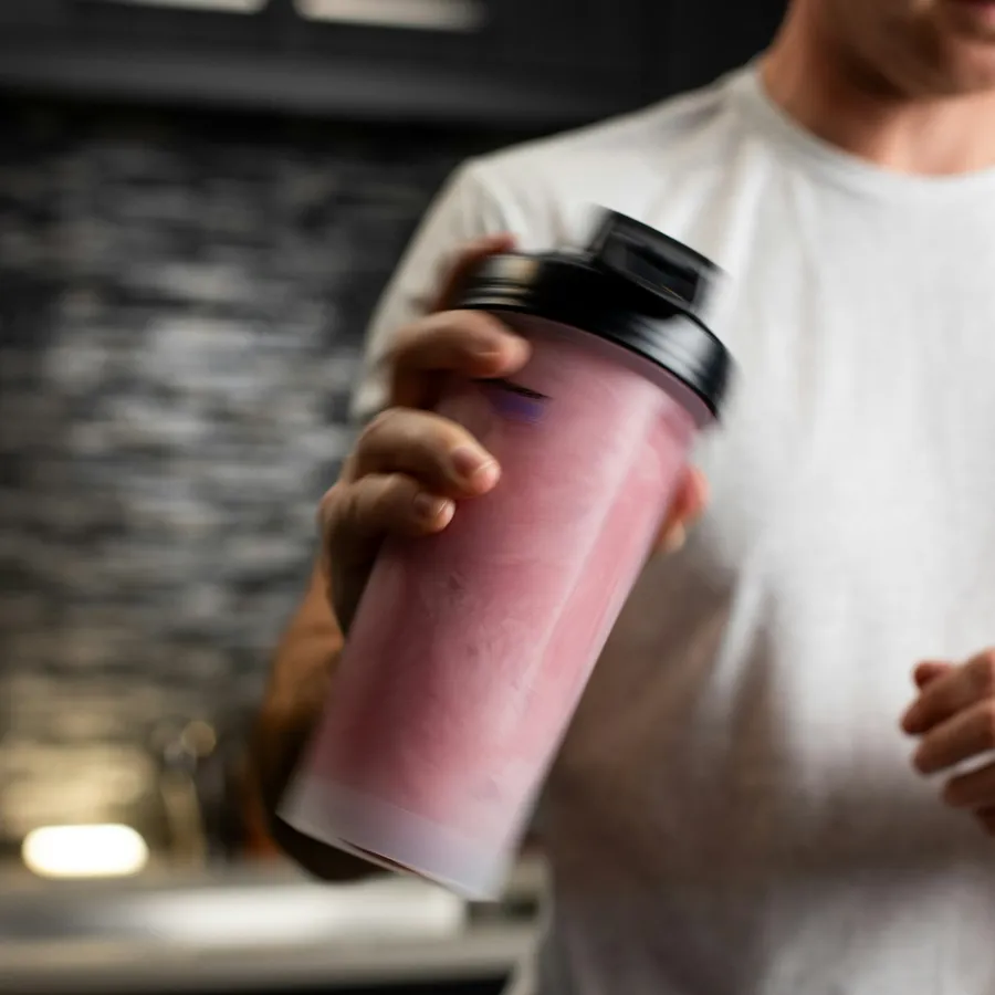 Hombre preparando un batido de mass gainer en un shaker